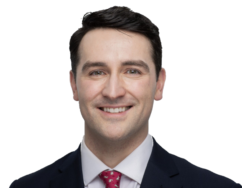Dr Tom Walker in a dark suit and red tie.